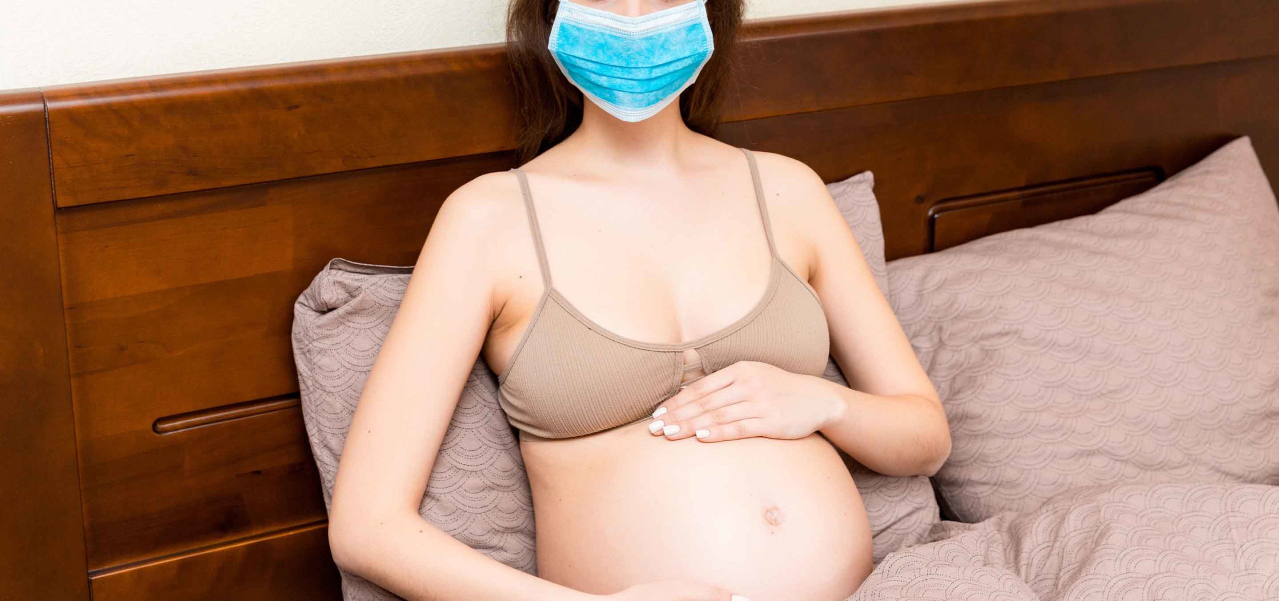 grávida sentada a utilizar máscara preventivamente contra o COVID-19