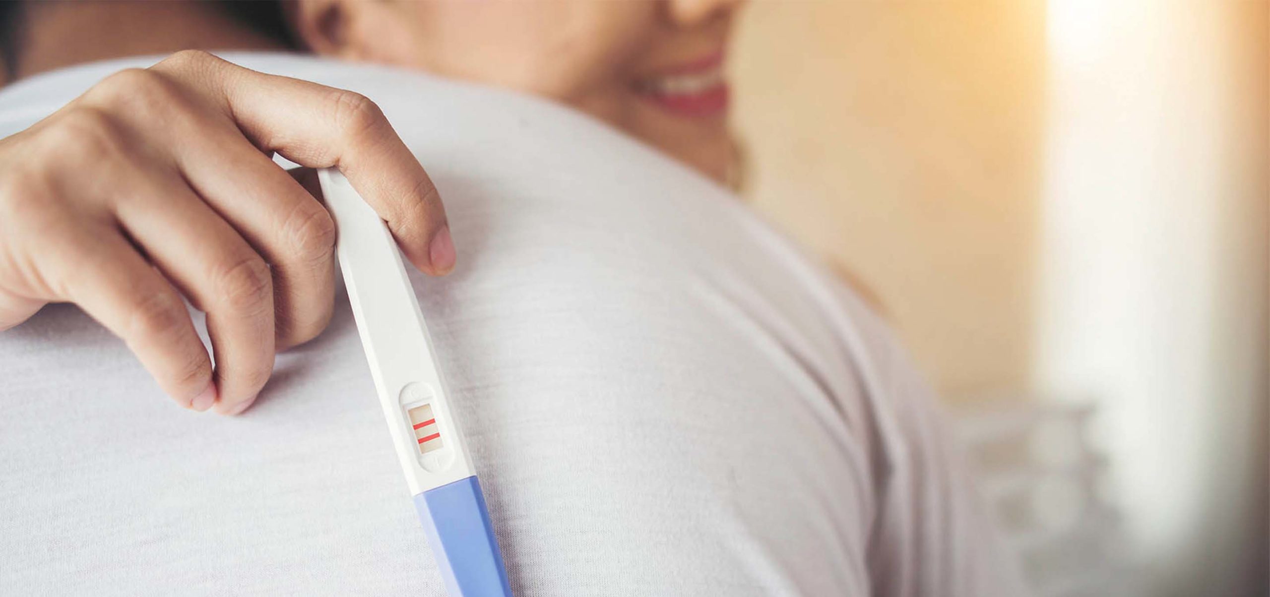grávida mostra teste de gravidez com resultado positivo