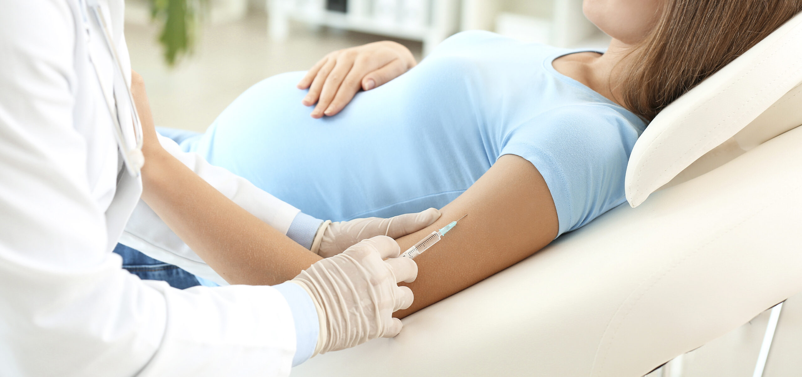 grávida deitada enquanto lhe é administrada uma vacina